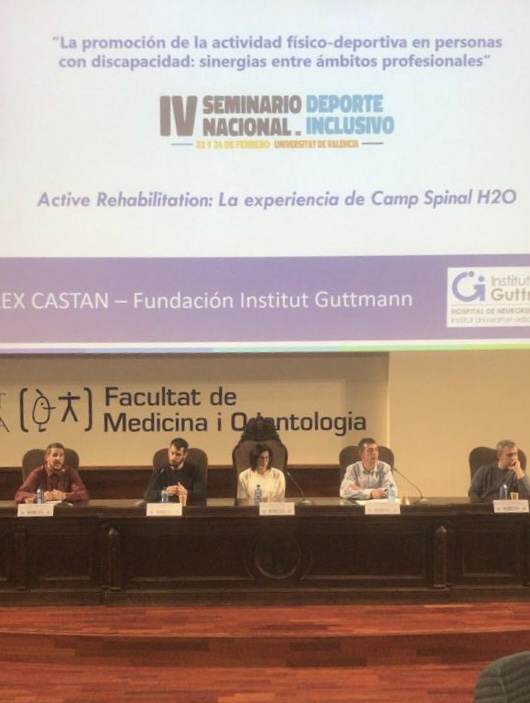 Foto de cuatro ponente en el anfiteatro de la facultad de medicina y odontología con la pantalla detrás proyectando diapositivas de presentación del seminario